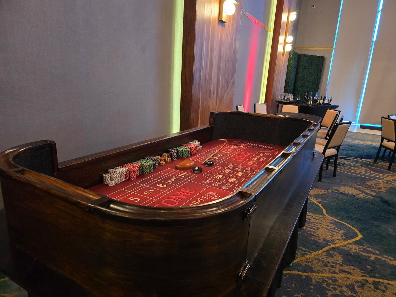 Red-felt craps table in a modern neon-lit Salt Lake City event space